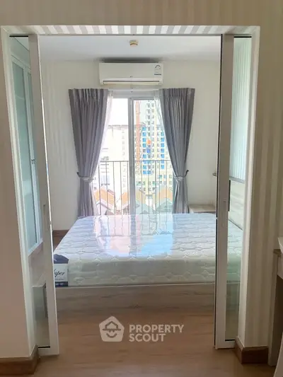 Modern bedroom with glass doors and city view, featuring a comfortable bed and stylish curtains.