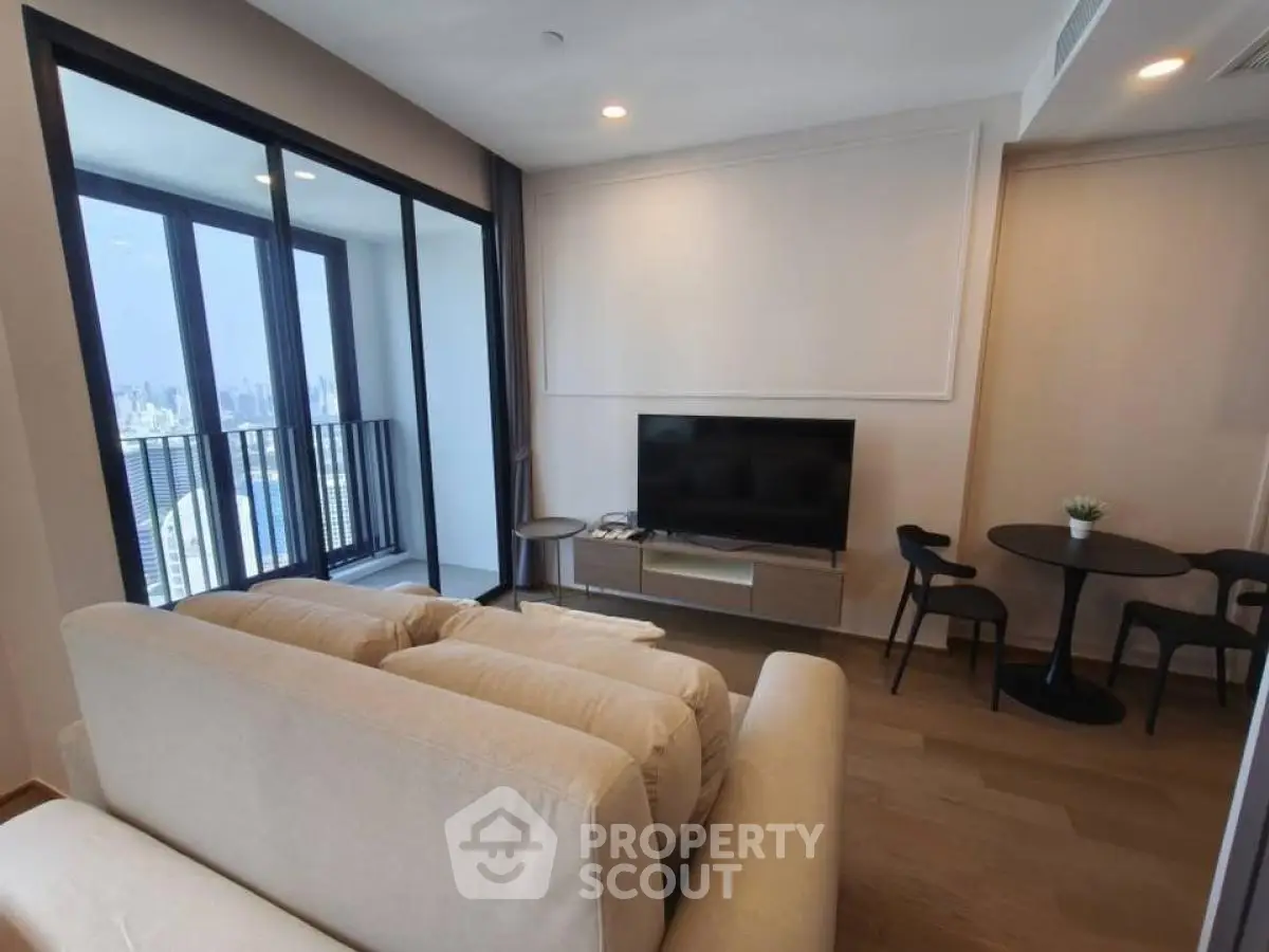 Modern living room with balcony and city view, featuring cozy seating and sleek decor.