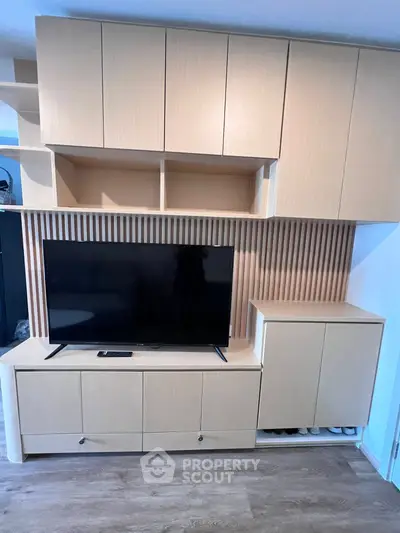 Modern living room with sleek wooden cabinetry and large flat-screen TV