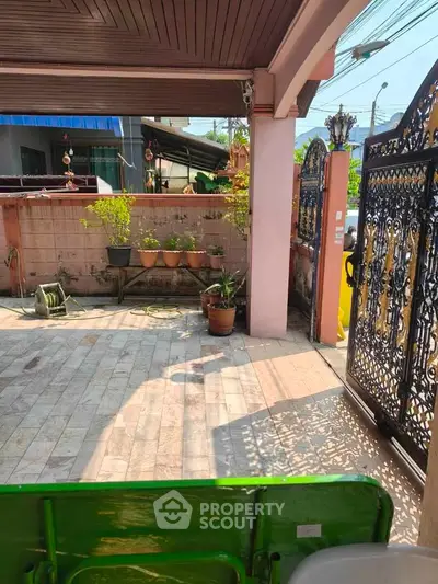 Charming residential entrance with decorative gate and potted plants, perfect for welcoming guests.