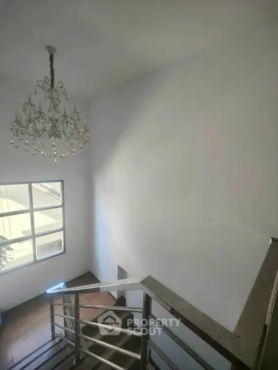 Elegant staircase with chandelier and large window in modern home