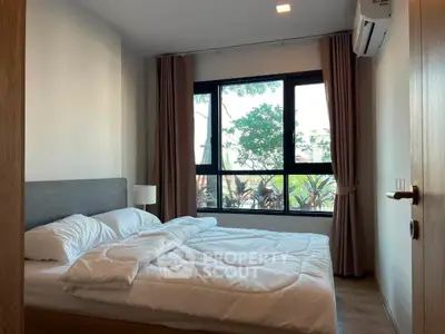 Cozy bedroom with large window and modern decor, perfect for relaxation and comfort.