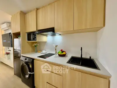 Modern kitchen with sleek wooden cabinets, induction cooktop, and integrated washing machine.