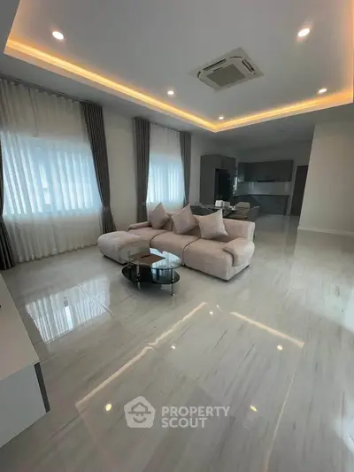 Spacious modern living room with elegant sofa and open kitchen layout, perfect for entertaining.
