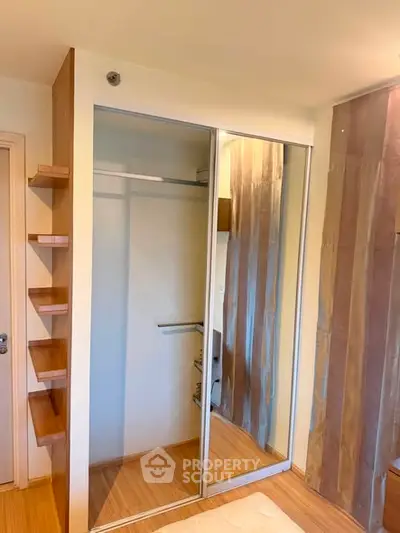 Modern bedroom with sleek mirrored closet and wooden shelving, perfect for stylish storage solutions.