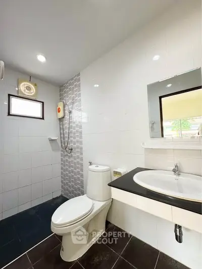 Modern bathroom with sleek fixtures and tiled walls, featuring a shower and vanity.