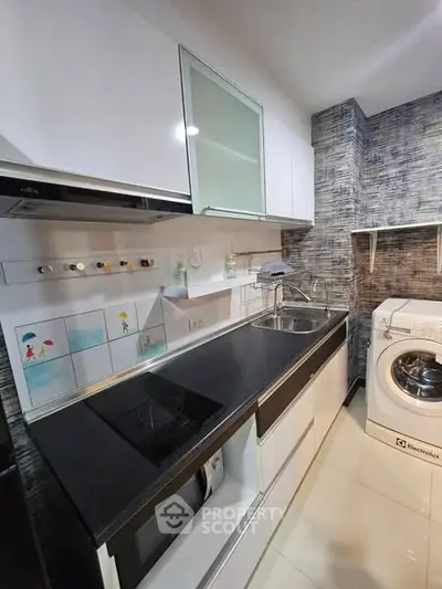 Modern kitchen with sleek cabinets and washing machine, featuring a stylish backsplash.