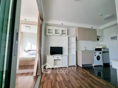 Modern open-plan living area with sleek kitchen and cozy bedroom view