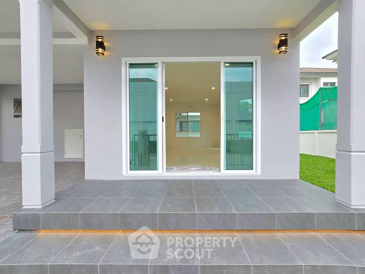 Modern home exterior with sleek sliding glass doors and spacious tiled patio.