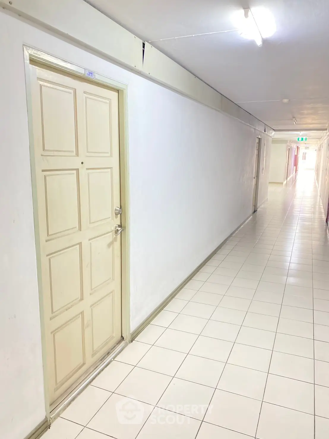 Bright corridor with tiled flooring and multiple doors in an apartment building.