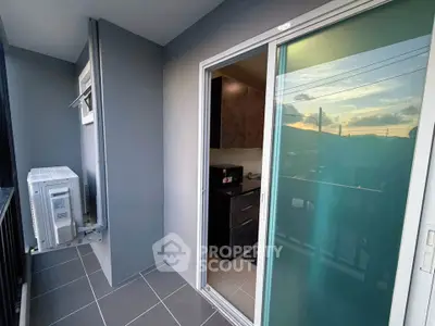 Modern balcony with sliding glass door and scenic sunset view, featuring sleek air conditioning unit.
