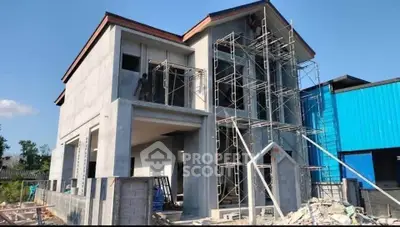 Modern two-story house under construction with scaffolding and clear blue sky.