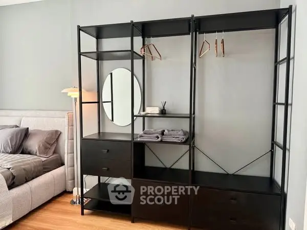 Modern bedroom with sleek black wardrobe and cozy bed setup.