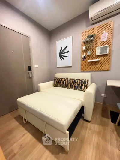 Cozy living room with modern sofa and stylish wall decor in a compact apartment.