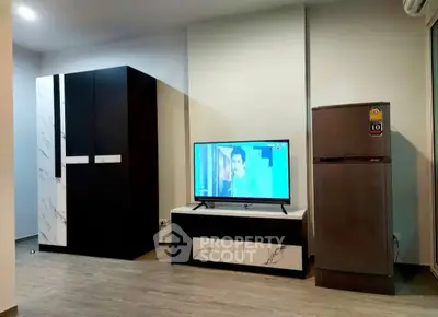 Modern living room with sleek furniture and flat-screen TV, featuring a stylish wardrobe and refrigerator.