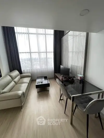 Modern living room with sleek furniture and large window offering natural light.