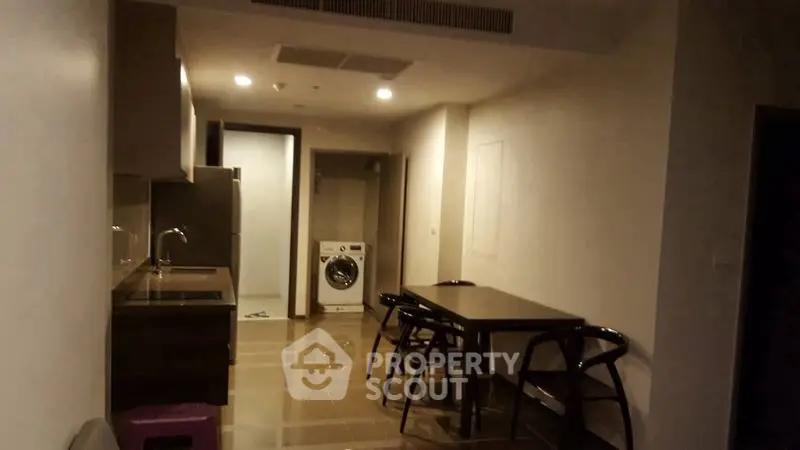Modern apartment interior with dining area and kitchen featuring a washing machine, ideal for urban living.