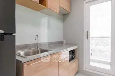 Modern kitchen with sleek cabinetry and balcony access in a stylish apartment.