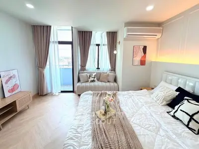 Luxurious bedroom with stylish decor and large windows offering natural light and a cozy seating area.