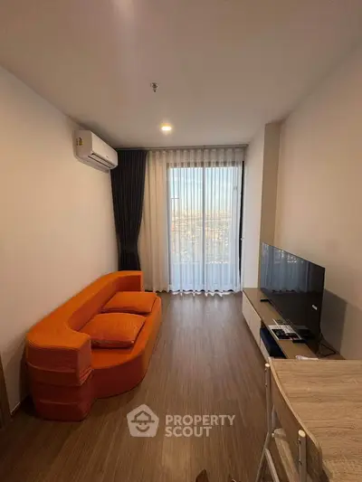 Modern living room with orange sofa and city view through large window.