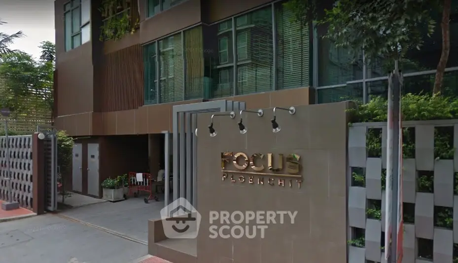 Modern building entrance with stylish facade and lush greenery at Focus Ploenchit.