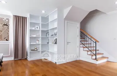 Elegant living room with built-in shelves and wooden staircase, perfect for modern living.
