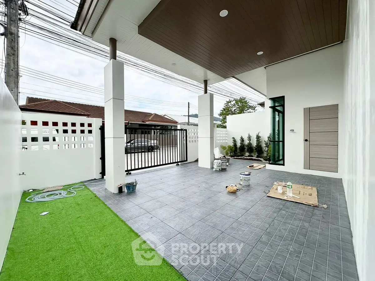 Modern exterior patio with tiled flooring and artificial grass in a stylish residential property.