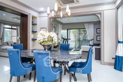 Elegant dining room with blue velvet chairs and marble table, open layout to living area, modern decor.