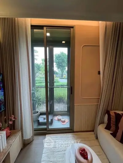 Cozy living room with sliding glass door leading to a small balcony with garden view.