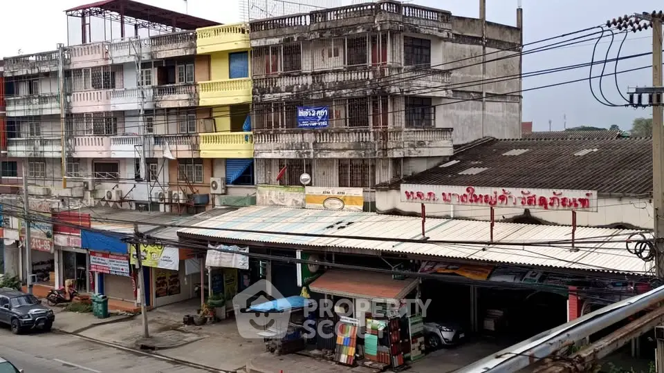 Street view of mixed-use buildings with shops and residential units in a bustling urban area.