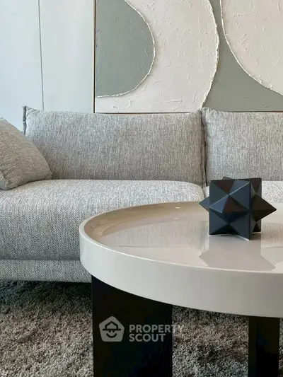 Modern living room with stylish gray sofa and geometric decor on round table.