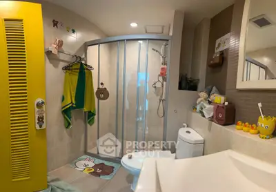 Charming bathroom with vibrant yellow door and playful decor, featuring a modern shower and cozy ambiance.