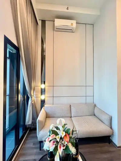 Modern living room with sleek design and cozy sofa, featuring elegant decor and large windows.