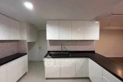 Modern kitchen with sleek white cabinets and black countertops in a contemporary home.