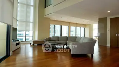Spacious modern living room with large windows and elegant furniture in a high-rise apartment.