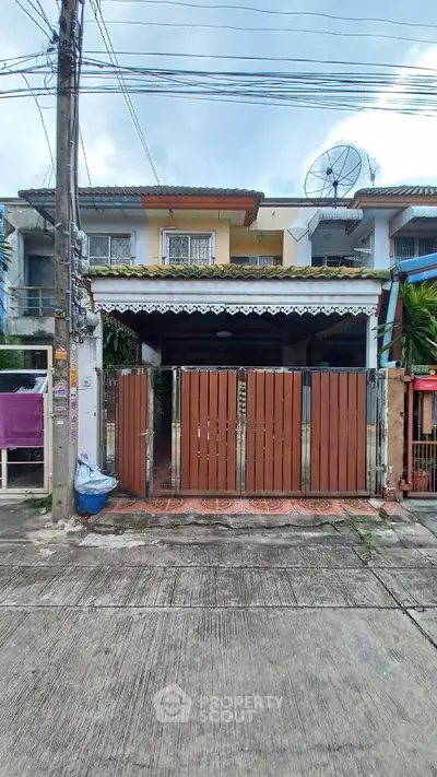 Charming townhouse with gated entrance and satellite dish in a quiet neighborhood.