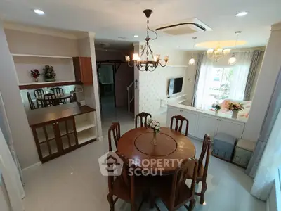 Elegant dining area with wooden table and chairs, chandelier, and cozy living space.