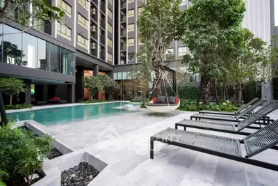 Luxurious apartment pool area with modern lounge chairs and lush greenery