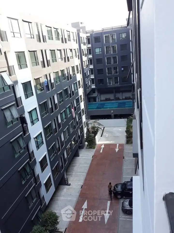 Modern apartment complex with pool and parking area, showcasing urban living.