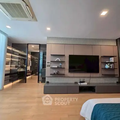 Luxurious modern bedroom with walk-in closet and sleek entertainment center.