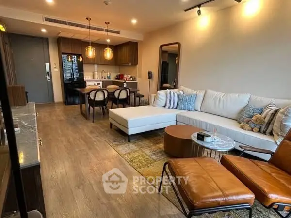 Modern living room with open kitchen, stylish furniture, and warm lighting.
