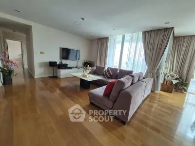 Spacious living room with hardwood floors and large windows in modern apartment.