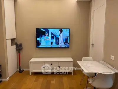 Cozy living room with wall-mounted TV, elegant dining set, and wooden flooring.
