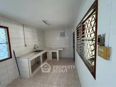 Spacious kitchen with tiled walls and open layout, featuring large windows for natural light.