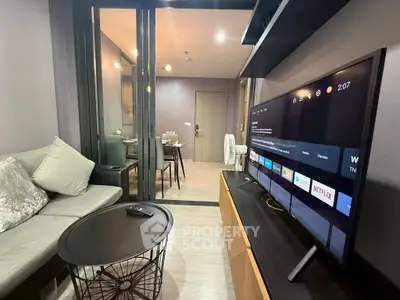 Modern living room with sleek TV setup and cozy dining area in open layout apartment.