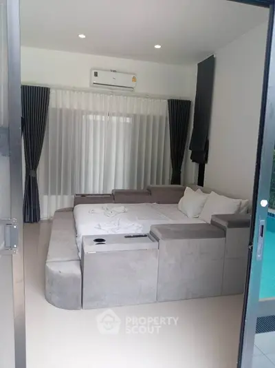 Modern bedroom with sleek design and pool view, featuring a cozy bed and elegant curtains.