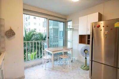 Bright kitchen with balcony view, modern appliances, and cozy dining area in urban apartment.