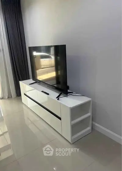 Modern living room with sleek TV stand and large flat-screen TV, perfect for entertainment.