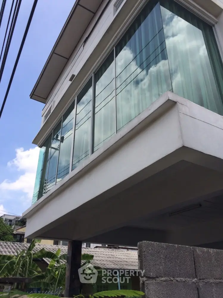 Modern architectural building with large glass windows and clear blue sky reflection.