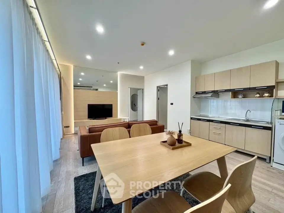 Modern open-plan living room and kitchen with sleek furniture and natural light.